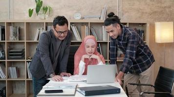 une équipe de jeunes collègues de démarrage qui sont des personnes islamiques discutent avec leur patron de projets financiers travaillant dans une entreprise de commerce électronique. utiliser un ordinateur portable pour communiquer en ligne via Internet dans un petit bureau. video