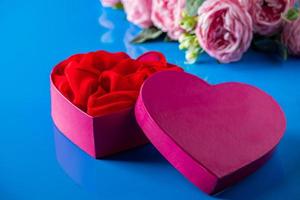 Heart shaped open gift box on blue background. photo