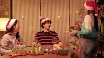 una comida especial para la familia, la joven sirve pavo asado a los amigos y alegre con bebidas durante una cena en el comedor de la casa decorado para el festival de Navidad y la fiesta de celebración de año nuevo.