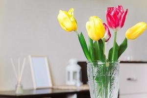 Bouquet of yellow and pink tulips in a glass vase. photo