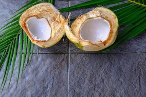 fruta de coco verde fresca cortada por la mitad y hojas de coco