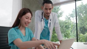 Healthcare team partners. Two uniformed young Asian ethnicity doctors are co-workers discussing medication in hospital's clinic office. Specialist persons are experts and professionals. video