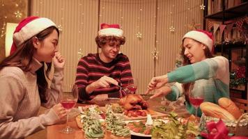 Freunde genießen es, am Tisch mit Spezialitäten zu essen, junge Frau, die im Speisesaal des Hauses gebratenen Truthahn schneidet, mit Ornamenten dekoriert, Weihnachtsfest und Neujahrsfeier.