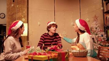 amigos se divertem comendo lanchonete à mesa com comidas especiais, uma jovem alimentando o homem na sala de jantar da casa, decorada com enfeites para o festival de natal e a festa de celebração do ano novo. video