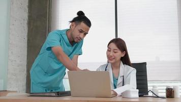 Healthcare team partners. Two uniformed young Asian ethnicity doctors are coworkers discussing medication in hospital's clinic office. Specialist persons are experts and professionals.