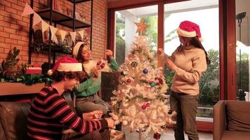 Family and friends together are happily decorating the white Christmas tree in the home's living room, fun and cheerful prepare for a celebration party for the New Year festival holiday. video