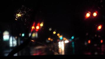Vista nocturna lluviosa en cámara lenta del movimiento de los limpiaparabrisas desde el interior de un automóvil en un semáforo en rojo video