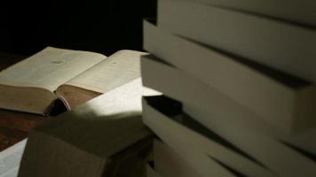 foto de estúdio de movimento de boneca com grandes livros empilhados sobre uma mesa à noite