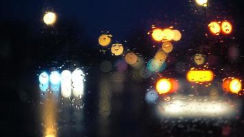 Vista nocturna lluviosa desde el interior de un automóvil en un semáforo en rojo