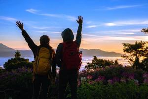 parejas asiáticas turistas con mochilas de pie mirando la vista del paisaje en la montaña, el hermoso paisaje y la luz del hermoso sol en el cielo