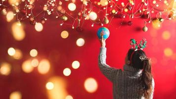 Merry Christmas and Happy New Year.The girl is designing with Holiday ornaments decoration. the christmas background red. with copy space for your text. Led lights photo