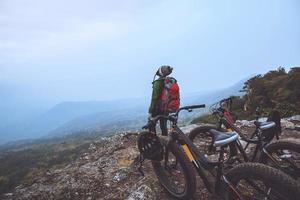 Asian women Travel photograph Nature. Travel relax ride a bike Wilderness in the wild. Standing on a rocky cliff. Thailand photo