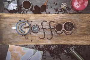 equipment material about coffee beans. Top view with copy space for your text. Coffee message write on a wooden table. Concept travel with map. photo