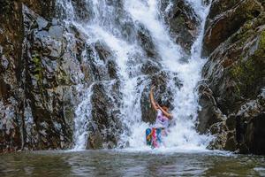chica viajando cascada de vacaciones. la niña que disfruta jugando felizmente en la cascada. viajar por la naturaleza, viajar relajarse, viajar a tailandia. cascada de huai toh en krabi. foto