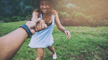 Lover women and men asians travel relax in the holiday. Hold hands running on the lawn. Wild nature wood on the mountain. photo