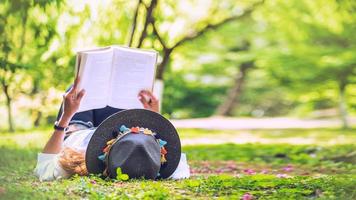 mujer viajera de la libertad acostada leyendo en el parque y disfrutando de una hermosa naturaleza. espacio para texto. foto