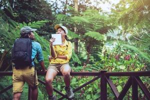 Asian couple travel nature walking relax and studying nature in the fores. photo