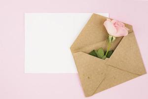 white blank card brown envelope with rose pink background photo