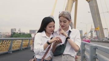 Frauen, die ein Smartphone benutzen, während sie auf einer Brücke stehen.
