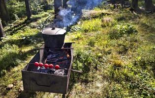 In the old cauldron on the barbecue cooking porridge against a forest clearing at noon photo