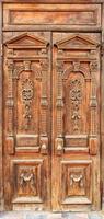 Old weathered wooden entrance doors with carved elements and a symmetrical pattern on the wings in the Ukrainian style. photo