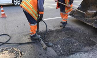 la brigada de trabajadores limpia una parte del asfalto con palas en la construcción de carreteras