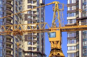 Grúa entre las fachadas y cerca del moderno edificio residencial en construcción. foto