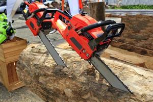 Red chainsaws are driven into the log. The concept of harvesting wood. photo