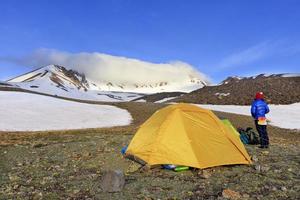 View of the tourist tent with a young girl and the mountain peak Erdzhiyas shrouded in dense fog. photo