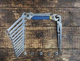 Set of combination wrenches and old adjustable wrenches on an old wooden background photo