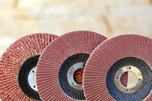 Flap grinding wheels of different grains on wood and metal on a light beige background in unsharp.