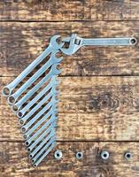 A set of chrome vanadium combination wrenches and an adjustable wrench on an old wooden background. photo