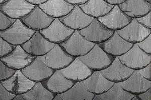 Background and texture of an old roof made of gray slate slabs in the form of fish scales. photo