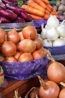 Various types of onions, yellow, white, red, are sold in trays on the market.