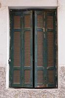 Wooden peeled shutters on an old window.