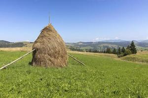 Stack of hay on a mountain meadow on a hillside. photo