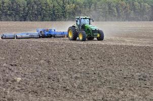 tractor en el campo cultiva el suelo después de la cosecha. foto