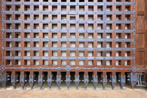 Las antiguas puertas de madera antiguas están cubiertas con barras forjadas y puntas dentadas al final.