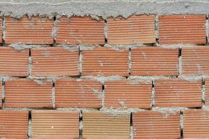 The pronounced texture of corpulent brick on the wall with a cement seam with cement hat. photo