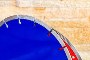 Segments of diamond cutting wheels on granite and reinforced concrete against the background of a yellow sandstone wall in blur. photo