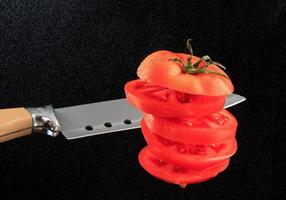 Flying chopped tomato in water dust on a black background. photo
