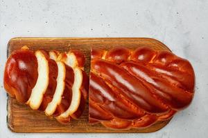 Homemade kalach lies on an old wooden cutting board on a concrete gray background. photo