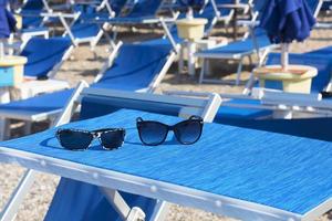 gafas de sol en una chaise longue azul brillante foto