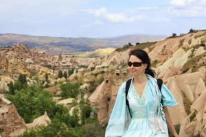 Portrait of a young beautiful woman in a turquoise dress against the background of a blurred landscape of mountain valleys and canyons of Cappadocia photo