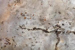 The texture of old weathered paint on a metal sheet with rusty spots, gouges and cracks.