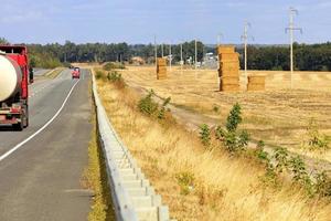 A busy road winds through harvested fields and green gardens on an autumn day. photo