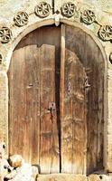 Puertas de madera arqueadas antiguas con un patrón de piedra y una cerradura de metal en el medio.