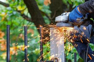 Bright, hot sparks fly out from under the protective cover of the angle grinder when cutting metal. photo