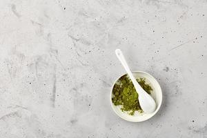 Matcha green tea powder in ceramic cup with white ceramic spoon. photo