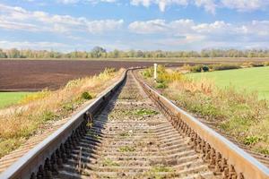 A single railroad track with a bend among the fields against the backdrop of a rural landscape. photo